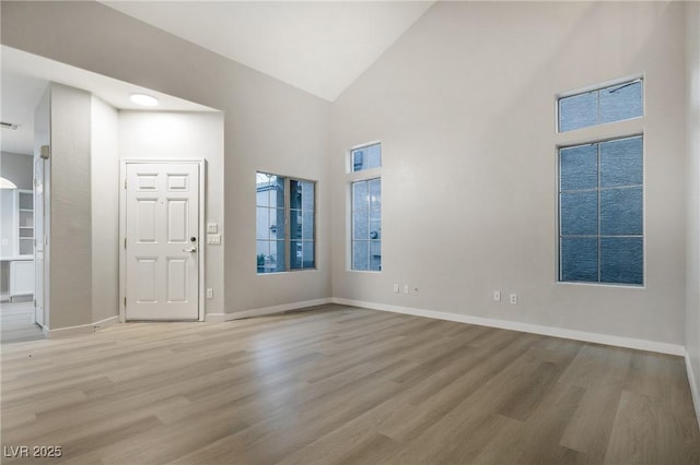 spare room with high vaulted ceiling and light hardwood / wood-style floors