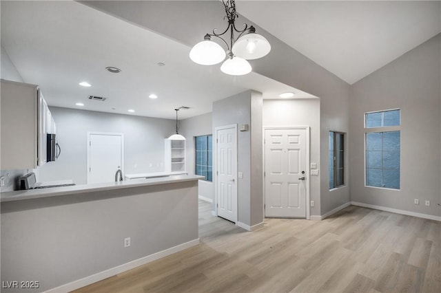 kitchen featuring vaulted ceiling, decorative light fixtures, sink, stove, and light hardwood / wood-style floors