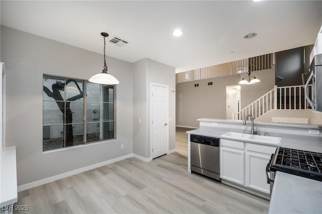 kitchen featuring sink, light hardwood / wood-style flooring, white cabinetry, stainless steel appliances, and decorative light fixtures