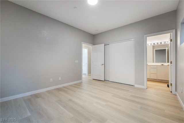 unfurnished bedroom with connected bathroom, a closet, and light wood-type flooring