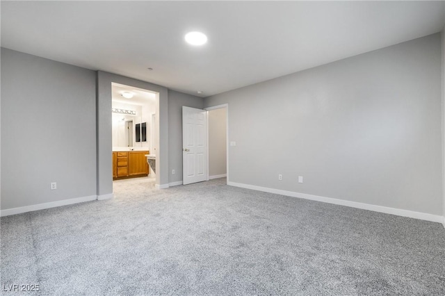 unfurnished bedroom featuring connected bathroom and light carpet