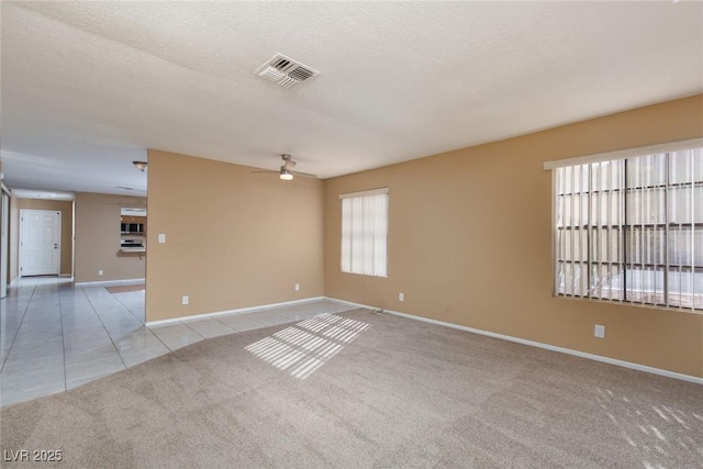 empty room featuring ceiling fan, a textured ceiling, and light tile patterned floors