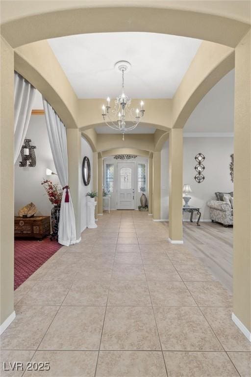 tiled entryway featuring a notable chandelier