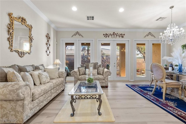 living room with ornamental molding, a notable chandelier, light hardwood / wood-style floors, and french doors