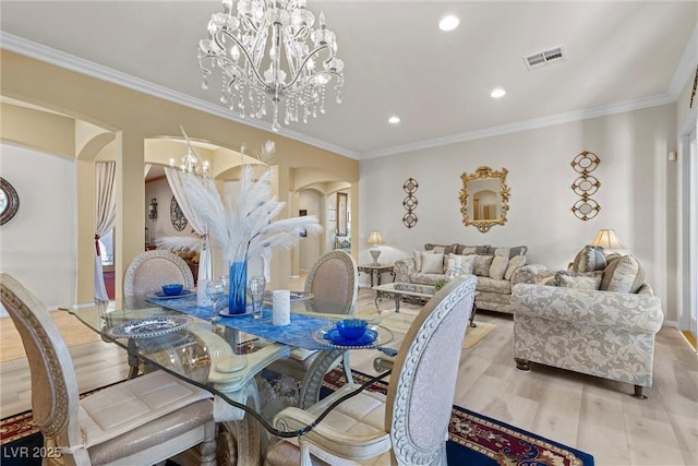 dining space featuring light hardwood / wood-style flooring, ornamental molding, and a chandelier