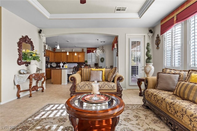 tiled living room with a notable chandelier, crown molding, and a raised ceiling