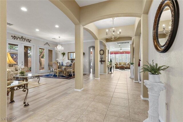 entryway featuring a notable chandelier, light tile patterned floors, ornamental molding, and french doors