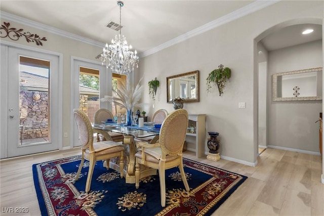 dining room with an inviting chandelier, ornamental molding, and light hardwood / wood-style flooring