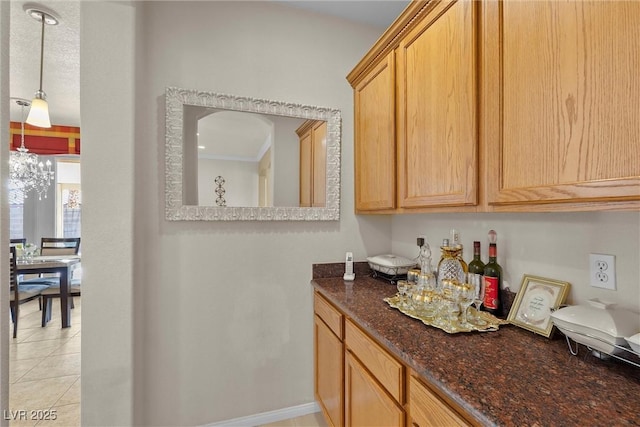 kitchen with a notable chandelier, light tile patterned floors, and dark stone countertops