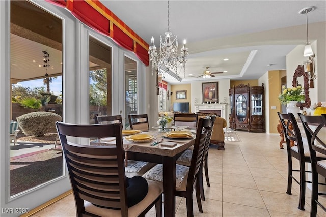 dining room featuring a raised ceiling, ceiling fan with notable chandelier, and light tile patterned floors