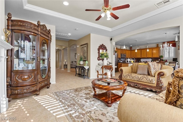 living room with a raised ceiling, ceiling fan with notable chandelier, sink, and light tile patterned floors