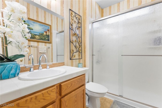 bathroom featuring vanity, a shower with door, and toilet