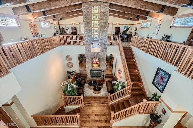 stairway with beamed ceiling, a healthy amount of sunlight, high vaulted ceiling, and hardwood / wood-style floors