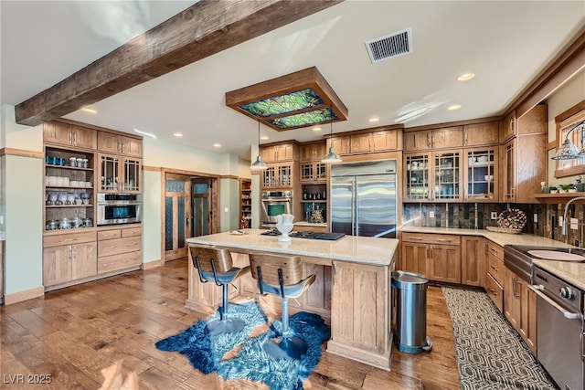 kitchen with sink, a kitchen island, beamed ceiling, stainless steel appliances, and backsplash