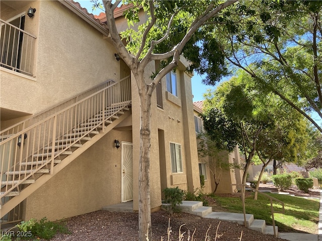 view of home's exterior featuring stucco siding, a tile roof, and stairway