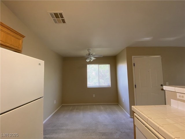 kitchen with white refrigerator, ceiling fan, tile counters, and light carpet