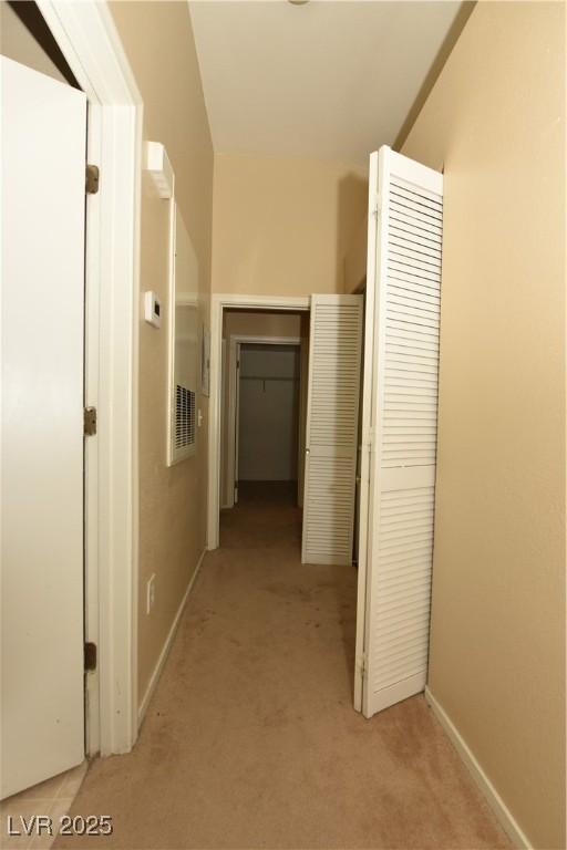 hallway featuring baseboards, light carpet, and visible vents