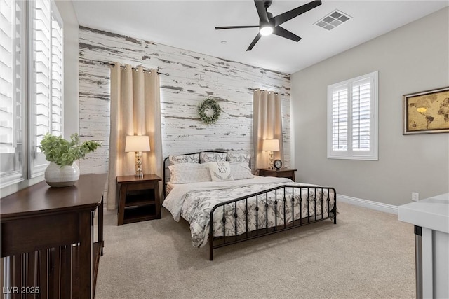 bedroom featuring visible vents, an accent wall, light carpet, baseboards, and wallpapered walls