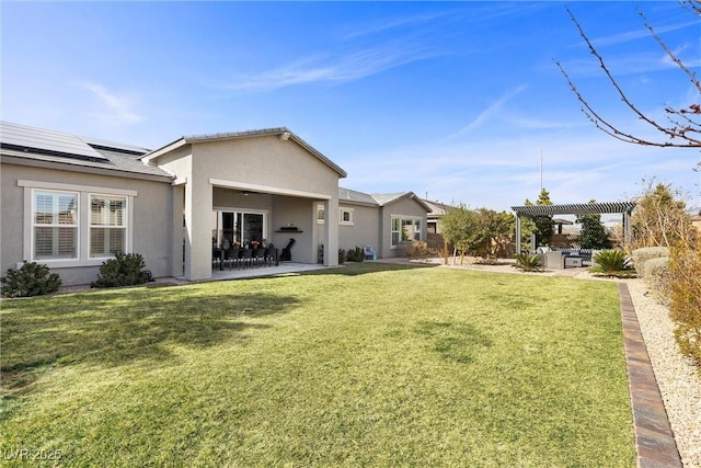 back of house with solar panels, a lawn, a patio area, a pergola, and stucco siding