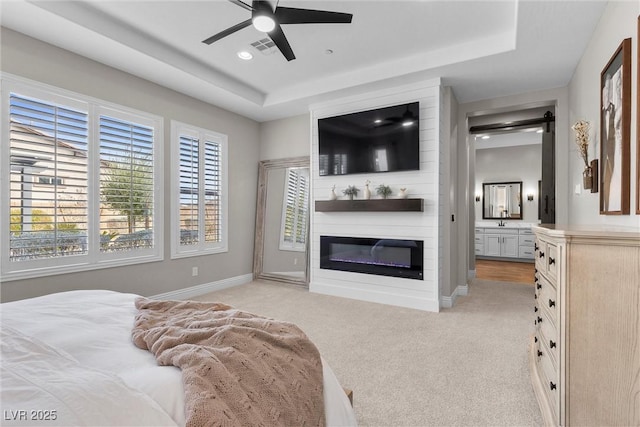 bedroom featuring light carpet, a fireplace, baseboards, and a raised ceiling