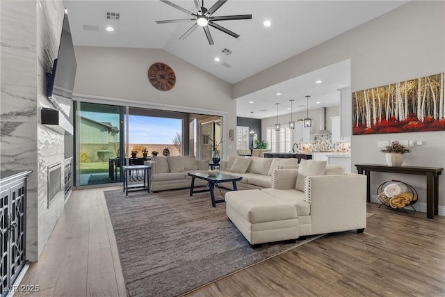 living area featuring ceiling fan, visible vents, wood finished floors, and a high end fireplace