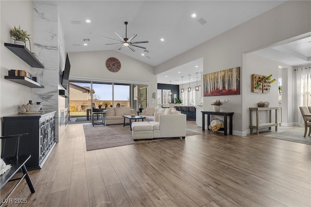 living area with high vaulted ceiling, recessed lighting, wood finished floors, and a healthy amount of sunlight