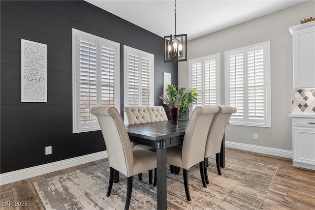 dining area featuring light wood-style floors, baseboards, and an inviting chandelier