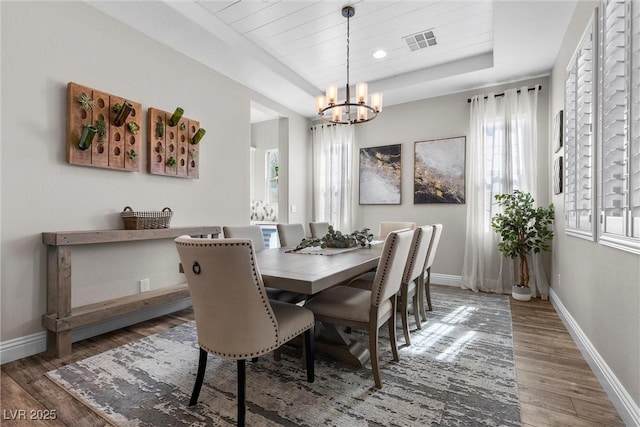 dining area featuring a wealth of natural light, a raised ceiling, visible vents, and wood finished floors