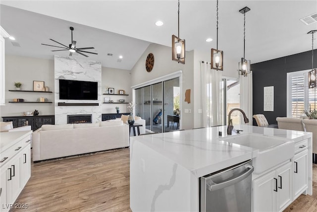 kitchen with visible vents, stainless steel dishwasher, a high end fireplace, open floor plan, and a sink