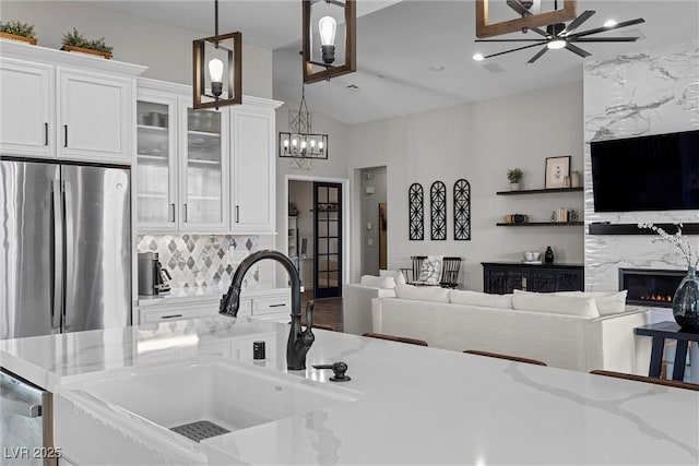 kitchen featuring white cabinetry, open floor plan, a sink, and decorative light fixtures