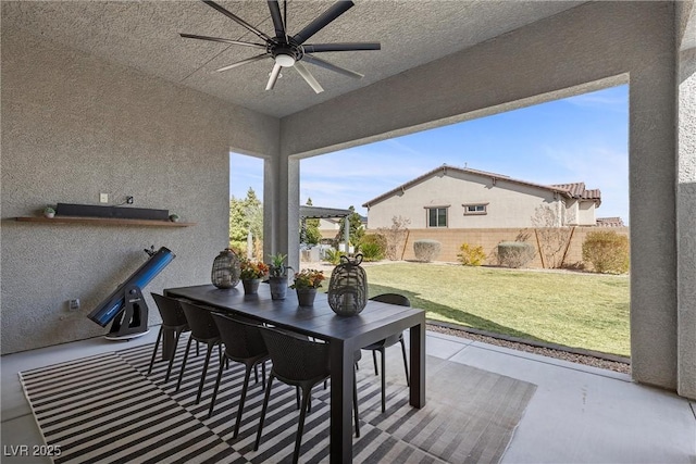 view of patio / terrace with ceiling fan, outdoor dining space, and fence