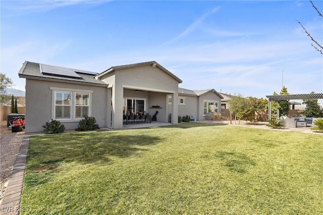 rear view of property with solar panels, a patio, a yard, a pergola, and stucco siding