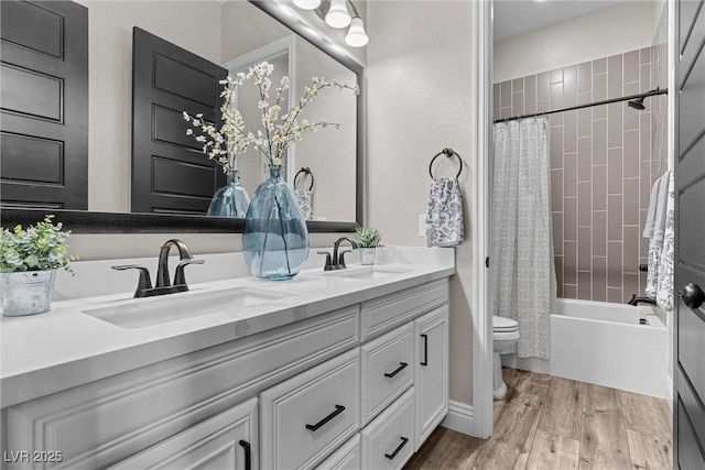 full bathroom featuring double vanity, wood finished floors, a sink, and toilet