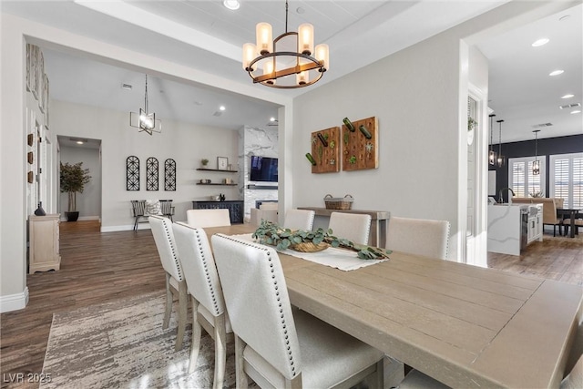 dining area with baseboards, recessed lighting, wood finished floors, and an inviting chandelier