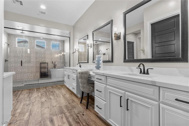 bathroom featuring a shower stall, visible vents, a sink, and wood finished floors