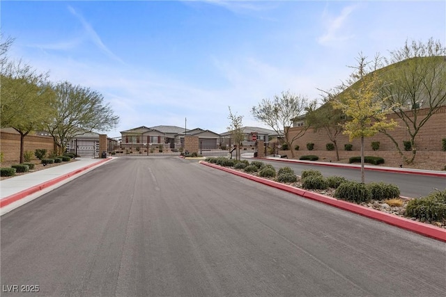 view of road featuring a gate, sidewalks, a gated entry, a residential view, and curbs