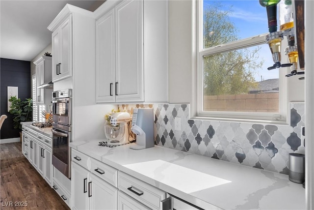 kitchen featuring stainless steel gas cooktop, dark wood-type flooring, white cabinetry, decorative backsplash, and light stone countertops