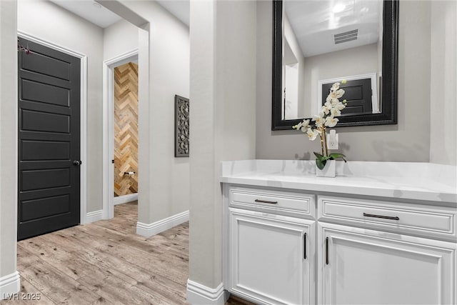 bathroom featuring visible vents, vanity, baseboards, and wood finished floors