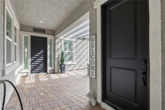 property entrance featuring stucco siding and a pergola