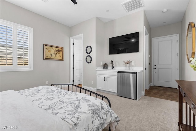 bedroom featuring light carpet, visible vents, baseboards, fridge, and wet bar