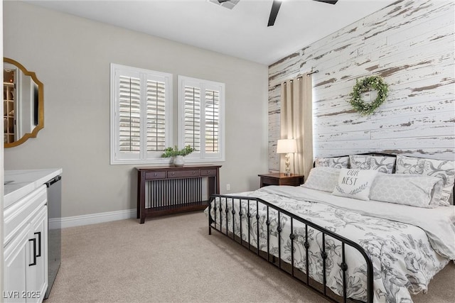 bedroom with light colored carpet, an accent wall, ceiling fan, wooden walls, and baseboards