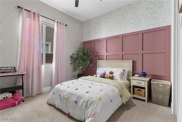 bedroom featuring light carpet, a ceiling fan, and a decorative wall