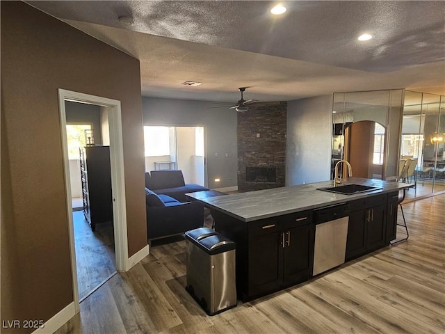 kitchen with sink, light hardwood / wood-style flooring, ceiling fan, a center island with sink, and stainless steel dishwasher