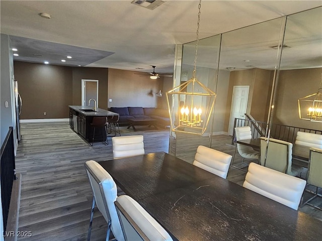 dining area with ceiling fan with notable chandelier, dark hardwood / wood-style flooring, and sink