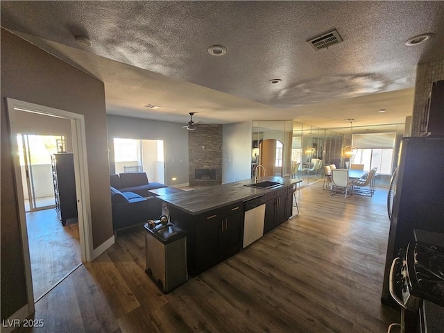 kitchen featuring dark hardwood / wood-style floors, an island with sink, sink, stainless steel appliances, and a textured ceiling