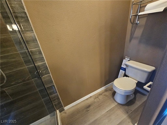 bathroom featuring hardwood / wood-style flooring, toilet, and a shower with door