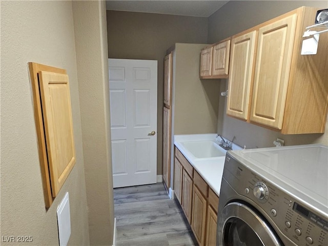 washroom featuring cabinets, washer / clothes dryer, sink, and light hardwood / wood-style flooring