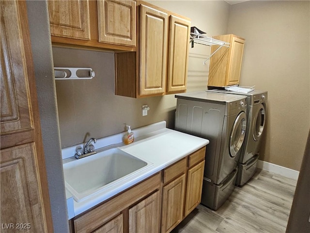 laundry room featuring sink, light hardwood / wood-style floors, cabinets, and washing machine and clothes dryer