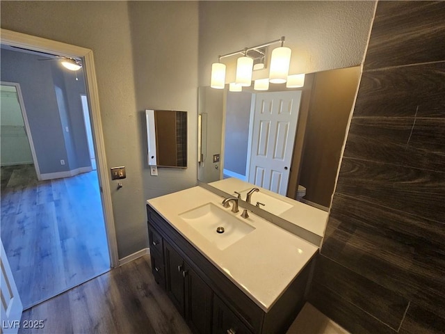 bathroom with toilet, baseboards, wood finished floors, and vanity