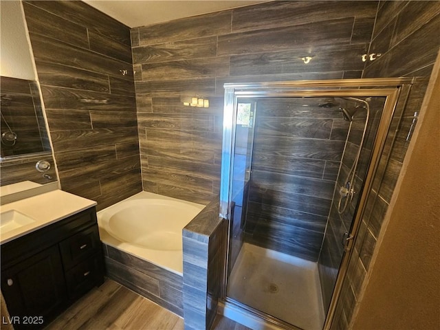 bathroom featuring a shower stall, wood finished floors, a garden tub, and vanity